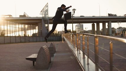 Successful young businessman runs overcoming obstacles in front of him. Entrepreneur or office worker rushing to work jumping over obstacles on the way. Stuntman in classic clothes. Slow motion