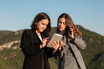 Focused businesswomen working on tablet and smartphone together