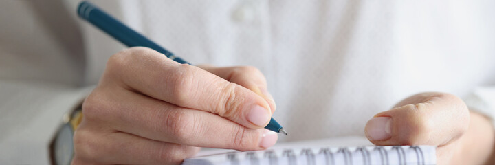 Female hand makes notes in notebook closeup