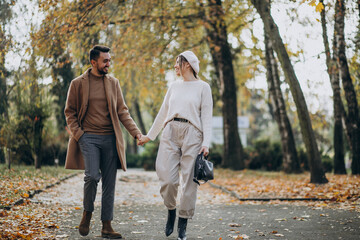 Fototapeta premium Young couple together in an autumn park