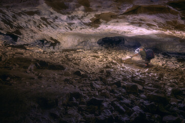 Fototapeta na wymiar Man explores a deep unexplored cave with backpack and lights