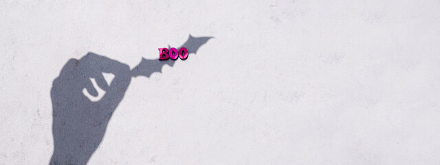 Trendy minimalistic concrete background for the Halloween holiday. Boo word. Black bat.