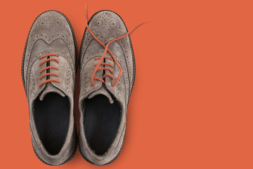 elegant men's suede shoes with orange laces, on an orange background, concept