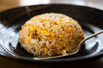黒いお皿にもられたチャーハン
