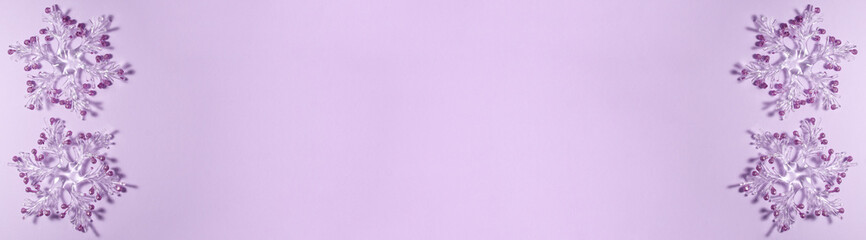 Banner of four transparent snowflakes with golden glitters at the tips on a purple background on the left and right side. Christmas concept lat lay top view with copy space