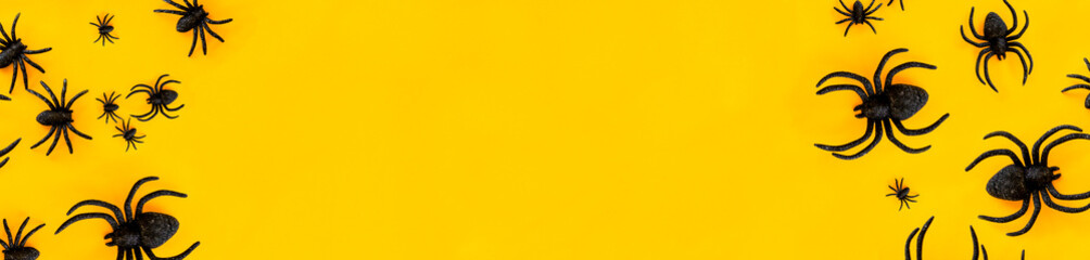 Flat lay banner of black horror spiders of different sizes directed in different directions on orange backdrop with copy space. Halloween decoration spooky background concept for holidays