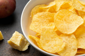 Potato Chips with cheese and onion in white bowl on rustic background