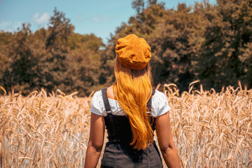 Femme de dos devant un champ de blé