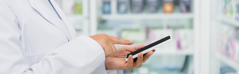 cropped view of pharmacist in white coat pointing at smartphone, banner