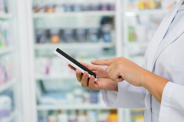 cropped view of pharmacist in white coat pointing at smartphone