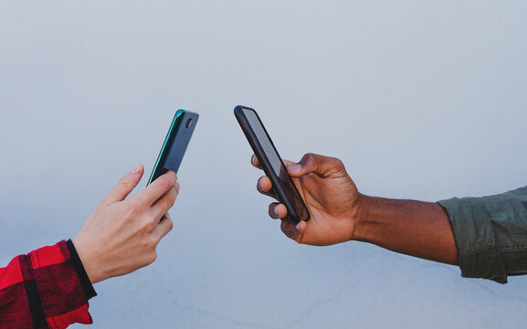 Close Up Of Young Biracial Couple Hands Using Smartphones On White Background