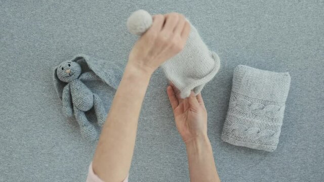 Cute composition with handmade knitted clothes romper and toy for newborn baby isolated on light blue background
