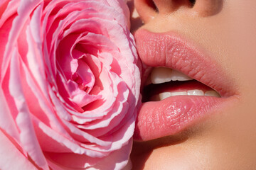 Sexy woman lips with pink lipstick and beautiful pink rose. Lips with lipstick closeup. Beautiful...