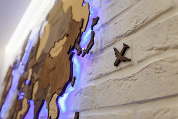 Wooden decorative world map with purple neon backlight on apartment wall. Modern interior design. Close up plane