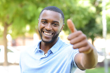 Happy black man gesturing thumbs up in a park