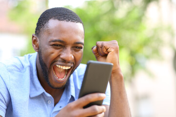 Excited black man checking smart phone