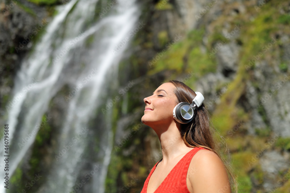Wall mural woman listening to music breathing in a waterfall - Wall murals