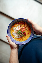 Chef holding a bowl of japanese curry chicken ramen with tomatoes