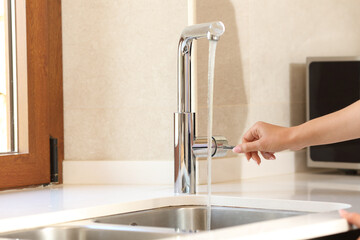 Woman hand opening kitchen faucet
