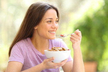 Happy woman eating cereal in terrace