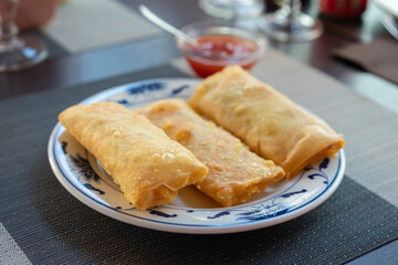 Traditional spring rolls fried on white plate at restaurant.background sweet chili sauce.
