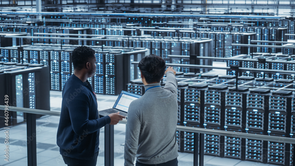 Poster two multiethnic male data center system administrators and it specialists talk, use laptop. informat