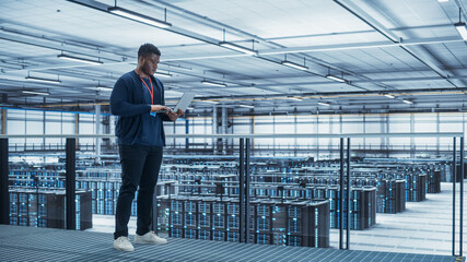 Data Center Engineer Using Laptop Computer. Server Farm Cloud Computing Specialist Facility with...