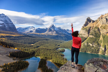 Naklejka premium Adventurous White Caucasian Woman Hikes in Canadian Rocky Mountains. Sunny Fall Day. Lake O'Hara, Yoho National Park, British Columbia, Canada. Adventure Travel Concept