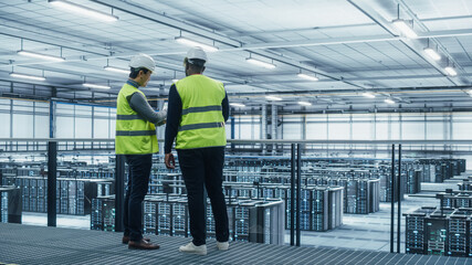 Korean Data Center System Administrators and African American IT Specialists in High Visibility Vests Talk, Use Laptop. IT Engineers work on Cyber Security Network Protection in Server Farm.