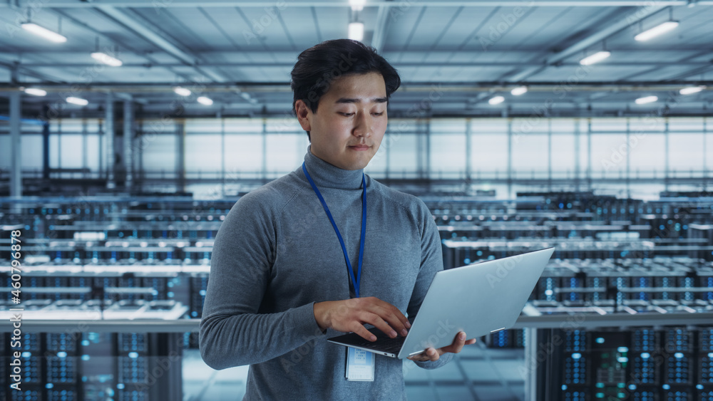 Poster Portrait of a Data Center Engineer Using Laptop Computer. Server Room Specialist Facility with Korean Male System Administrator Working with Data Protection Network for Cyber Security.