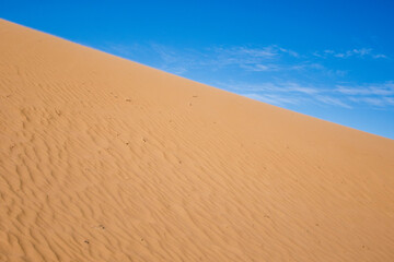 Ripple sand dunes and blue sky background. Desert landscape, sandy waves. Nature.
