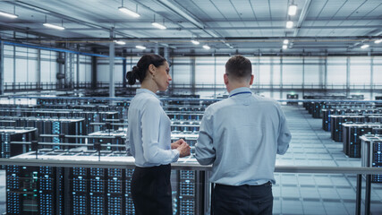 Data Center Female System Administrator and Male IT Specialist Talk, Use Tablet Computer....