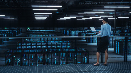 Data Center Engineer Using Laptop Computer. Server Farm Cloud Computing Specialist Facility with Multiethnic Female System Administrator Working with Data Protection Network for Cyber Security.