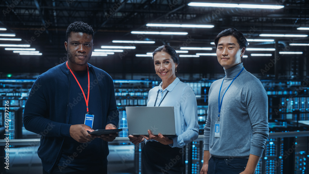 Poster Diverse Team of Data Center System Administrators and IT Specialists Use Laptop and Tablet Computers, Smiling on Camera. IT Engineers work on Cyber Security Protection in Cloud Computing Server Farm.
