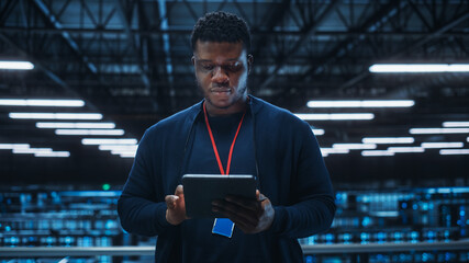 Portrait of a Data Center Engineer Using Laptop Computer. Server Room Specialist Facility with...