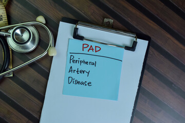 PAD - Peripheral Artery Disease write on sticky notes isolated on Wooden Table.