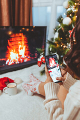 woman taking picture on the phone near christmas tree and fire place