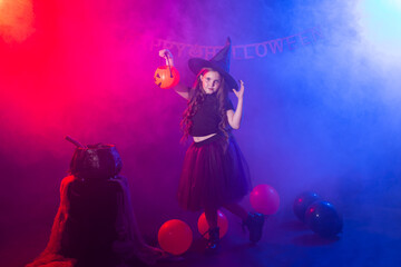 Funny child girl in witch costume for Halloween with pumpkin Jack.