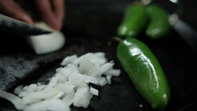 Hands slicing onion and green chili peppers on a traditional Mexican comal