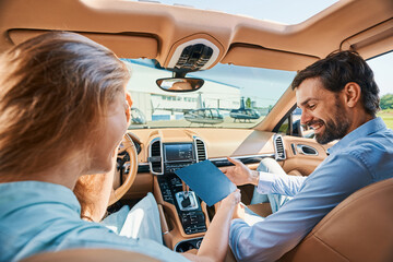 Joyous man getting present in luxury automobile parked at heliport