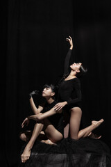 Fototapeta na wymiar Modern ballet performance. Two beautiful girls, modern dancers in art performance isolated on dark background. Feelings, emotions concept