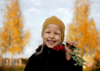 a little girl holds a red rowan in her hands and smiles