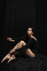 Portrait of young beautiful girl, modern ballet dancers posing isolated on dark background. Feelings, emotions concept