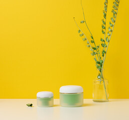 green jar for cosmetics on a white table. Packaging for cream, gel, serum, advertising and product promotion