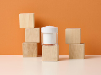 empty white jar for cosmetics on white table, orange background. Packaging for cream, gel, serum, advertising and product promotion. Mock up