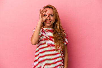 Caucasian blonde woman isolated on pink background excited keeping ok gesture on eye.