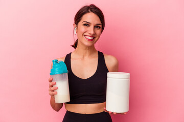 Young caucasian woman drinking a protein shake isolated on pink background
