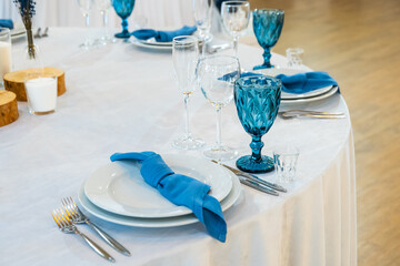 Detail of a wedding dinner setting. banquet table setting with blue napkins and glasses cutlery