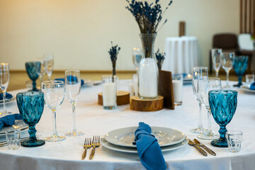 Detail of a wedding dinner setting. banquet table setting with blue napkins and glasses cutlery