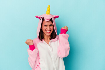 Young caucasian woman wearing an unicorn pajama isolated on blue background